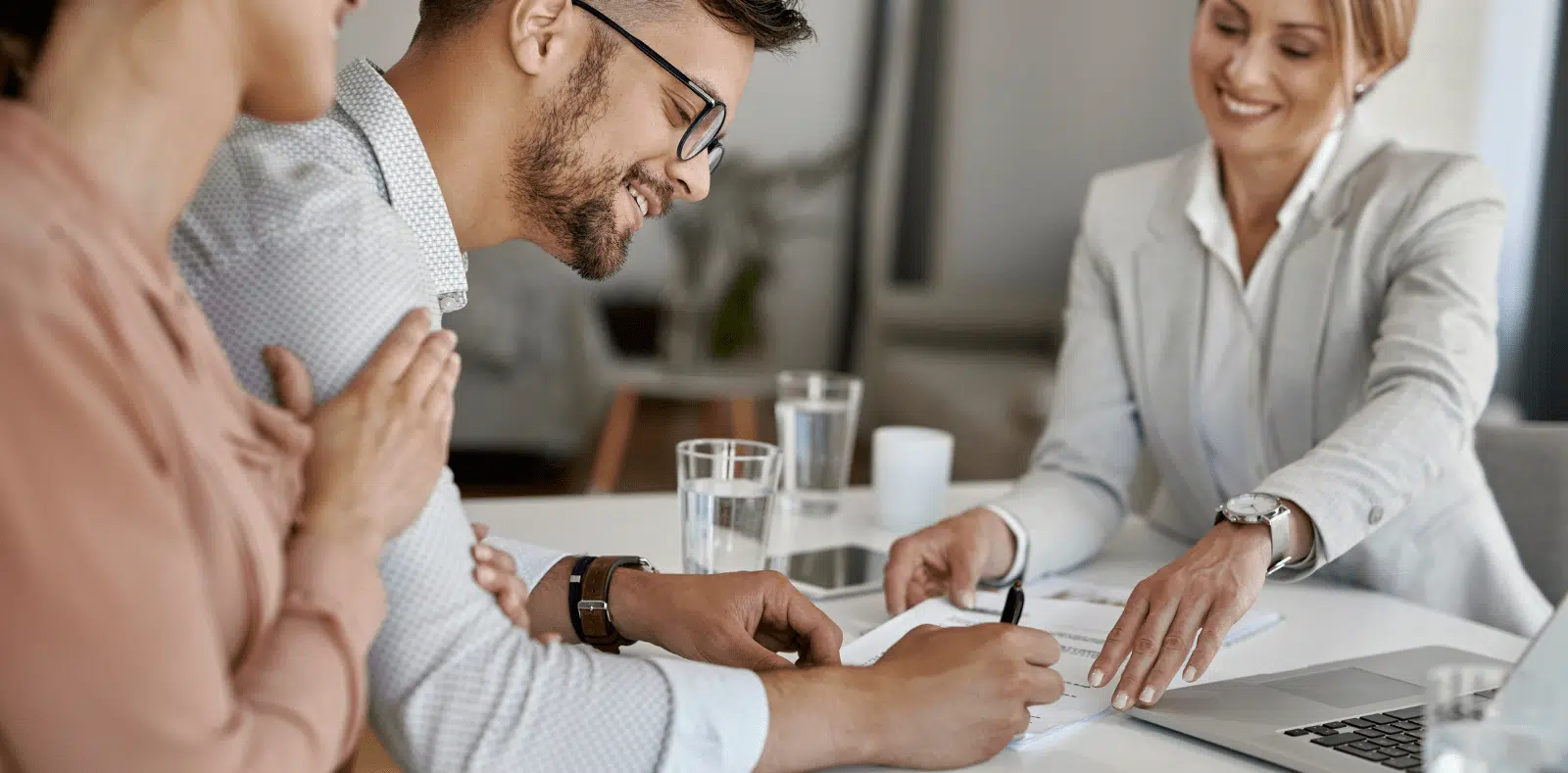 Two hands exchange a thick fan of $100 bills in a dimly lit setting with a blurred crowd in the background